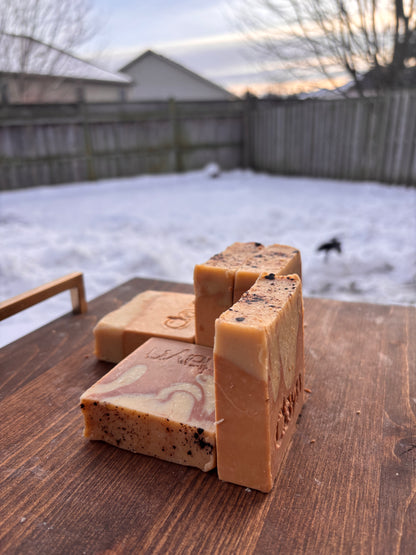 Three pieces of soap on a wooden surface with a snowy backyard background