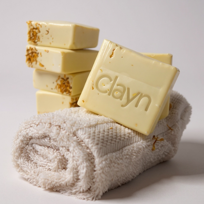Yellow soap bars with 'clayn' branding on a white towel against a light gray background