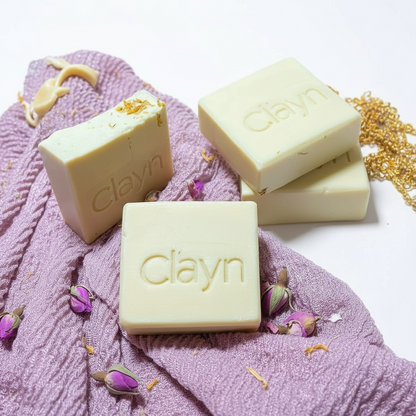 Clayn soap bars on a pink textured surface with flowers.